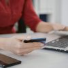 Startup employee doing online shopping with credit card on laptop, using banking money to purchase on sale. Office employee making transaction for e commerce development. Close up.